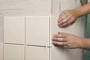 Two hands pressing on tile on wall