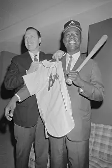 Hank Aaron Prints: Hank Aaron Being Assisted with Uniform Shirt and Baseball Bat