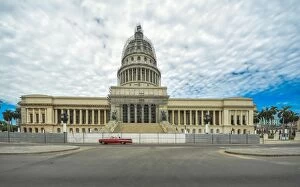 Images Dated 10th August 2016: Havanas Capitol building with red vintage car and dramatic sky, Cuba