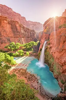 Green Prints: Havasu Falls in Arizona plunges in turquoise waters as the sun rises above the cliffside