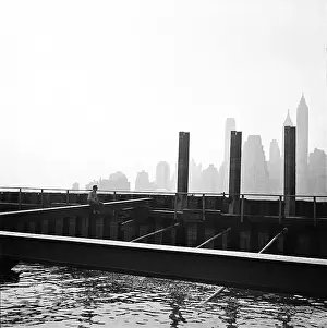 Prints of BROOKLYN, NY - MARCH 1958: famed fashion photographer Hiro Wakabayashi sits on a beam on the Brooklyn waterfront (now called DUMBO) in March 1958 in New York City, New York Portraits, Artworks, and Montages from a Visionary Photographer: Hiro Wakabayashi In Brooklyn