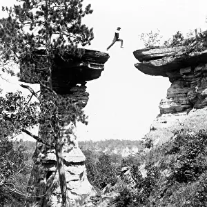 Time Captured: Vintage Art: Historic photograph of man leaping between boulder in mid-air