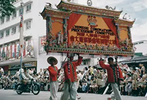 Prints of A procession in Hong Kong to celebrate the coronation of Queen Elizabeth II in London, June 1953. The Chinese Coronation Procession Committee march by with a large sign Queen Elizabeth II Prints: Hong Kong Celebration