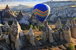 Images Dated 27th September 2015: Hot air balloons flying above rock formations in Red Valley, Goreme National Park, Goreme