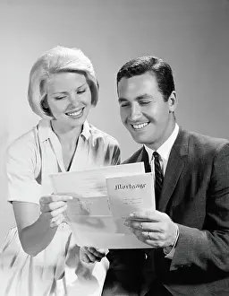 Husband and wife homeowners looking at mortgage and smiling