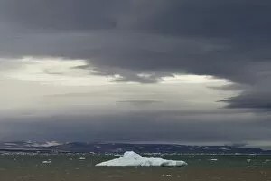Iceberg floating in Palanderbukta fjord during strong winds and storm clouds, Nordaustlandet, Svalbard Archipelago