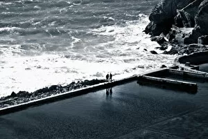 Two individuals meet on a sea wall