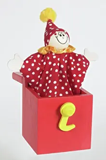 Comedy Prints: Jack in a box, smiling clown puppet popping out of red wooden box with arms extended to sides