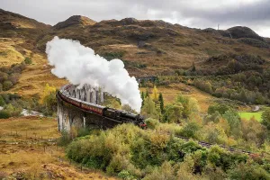 Prints of An image of the Jacobite steam train crossing over the Glenfinnan Viaduct in Autumn. Steam can be seen exiting the trains stack. The Train and Viaduct were used in the Harry Potter film series Steam Locomotive Prints: The Jacobite Steam train Crossing the Glenfinnan Viaduct in Scotland