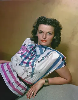 Prints of Actress Jane Russell pictured leaning back, supported by her left arm, USA, circa 1955. Russell is wearing a white, pink and blue printed top, silver-coloured ring and bracelet Hollywood's Sultry Siren – A Photographic Tribute: Jane Russell