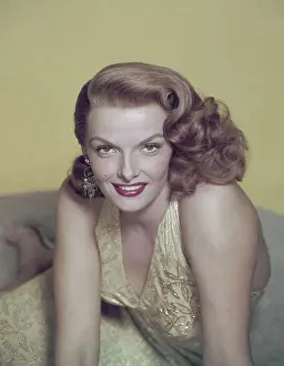 Prints of Actress Jane Russell pictured leaning forward, supported by both hands, USA, circa 1950. Russell, smiling, is wearing a yellow embroidered dress and silver-coloured earrings Hollywood's Sultry Siren – A Photographic Tribute: Jane Russell
