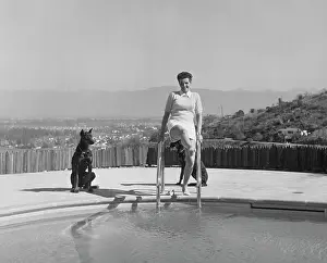 Prints of American actress Jane Russell leans on the ladder of a pool as she lifts one leg up with her two Doberman dogs, Blitz and Katherine, by her side, US, 1949 Hollywood's Sultry Siren – A Photographic Tribute: Jane Russell