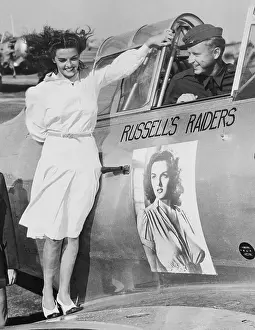 Prints of (Original Caption). July 13, 1941 - Stockton, California: Motion picture beauty Jane Russell inspects her own insignia on the training plane of Don Brown, son of gap-mouthed screen comic Joe E Hollywood's Sultry Siren – A Photographic Tribute: Jane Russell Standing on Airplane with Her Insignia