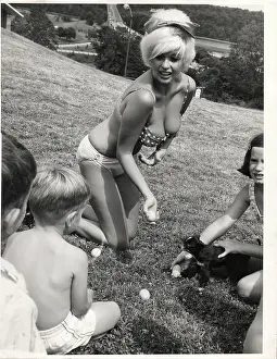 Prints of NEW YORK - 1964: Actress and model Jayne Mansfield poses for a portrait while playing on the grass with children in 1964 in New York City, New York Hollywood's Blonde Bombshell in Focus: Jayne Mansfield Portrait Session