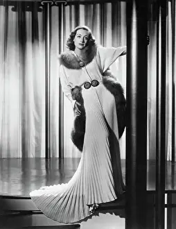 Prints of (Original Caption). Unusual Negligee for Joan. A white sunburst pleated skirt features this unusual negligee with its drape trim of red fox, designed for Joan Joan Crawford by Adrian A Glamorous Life Captured: Joan Crawford Posing in Pleated Skirt with Negligee