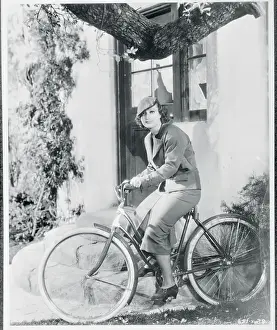 Prints of (Original Caption). Wheeling Mode. When enjoying a bicycle ride, Joan Crawford, MGM star, wears this blue cloth skirt, pleated at front and back, with a short suede jacket A Glamorous Life Captured: Joan Crawford Riding Bicycle