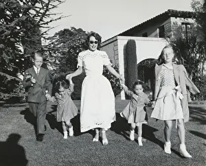 Prints of (Original Caption). Joan Crawford and four children, Christopher, Cathy, Cynthia, and Christina romp on lawn following party given by Ann Rutherford for daughter Gloria's 5th birthday A Glamorous Life Captured: Joan Crawford Walking with Her Children