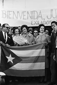 Juana Castro Holding Flowers Behind Cuban Flag
