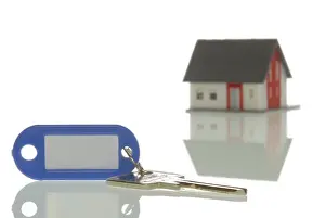 Hand Prints: Key lying in front of a miniature house, symbolic image for property market