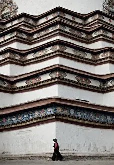 Lady walking in front of Tibetan Stupa