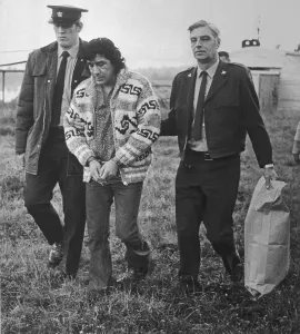 Vancouver Prints: Law Enforcement Officers with a Handcuffed Leonard Peltier