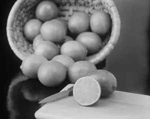 Lemon in basket, whole and half cut on chopping board with knife