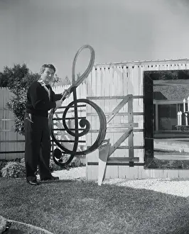 Liberace Prints: Liberace Standing Next to His Musical Fence