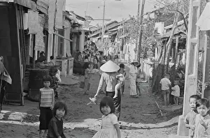 Prints of Vietnamese women, some wearing traditional non la hats, and children on a rundown street, with some of the children looking at the camera, in Saigon, Vietnam, 30th August 1965 Vietnam Prints: Life In Saigon