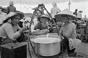 Prints of Vietnamese women, some wearing traditional non la hats, eating as they sit near a cooking pot on an embankment of the Saigon River as it flows through Saigon, Vietnam, 30th August 1965 Vietnam Prints: Life Along The Saigon River