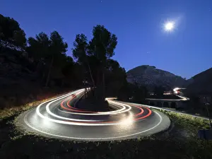 Headlight Prints: Lights of vehicles in movement circulating along a carretera with curves very closed in the moonlight