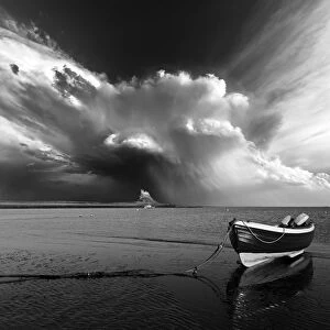 Lindisfarne Castle with a boat and a dramtic stormy sky. Northumberland. UK. Europe