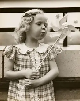 Little girl blowing on pin wheel toy