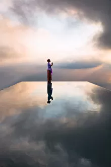 Images Dated 31st August 2019: Local woman praying at sunset, reflected into water, Bali