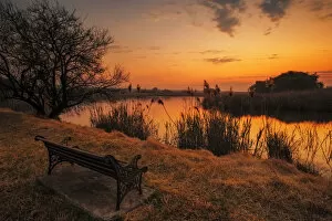 Lonesome park bench at sunset on the shores of a remote farm lake near Magaliesburg, Gauteng Province, South Africa