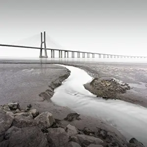 Motion Blur Prints: Long exposure of the famous bridge Ponte Vasco da Gama at low tide on the river Tejo with a small water tributary