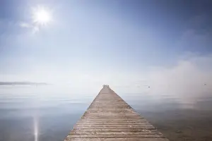 High Fog Prints: Very long jetty on Chiemsee Lake with high fog and sun near Seebruck