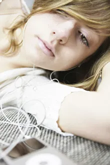 Portability Collection: Lying young woman listening to music with MP3 player and headphones