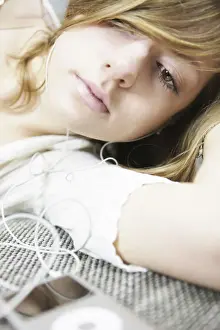 Electronic Prints: Lying young woman listening to music with MP3 player and headphones
