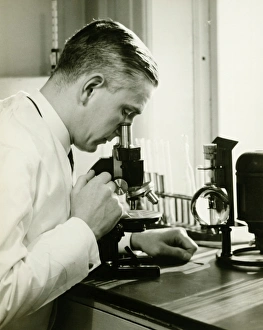 35 39 Years Collection: Male doctor using microscope in surgery, (B&W)