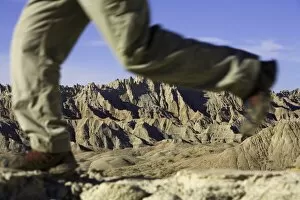 Male hiker walking in badlands, low section (focus on rock formations)