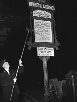 Man Changing Train Station Sign with Pole