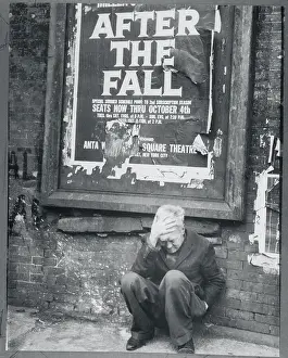 Man Crouching Beneath a Tattered Poster
