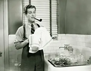 30 35 Years Prints: Man doing washing dishes in kitchen, pipe in teeth, (B&W)