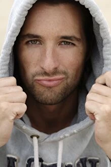 Satisfaction Gallery: Man, early 30s, wearing a hooded sweater in bad weather at the beach, portrait
