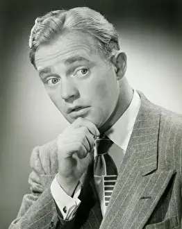 Man with hand on chin, looking away, close-up, studio shot