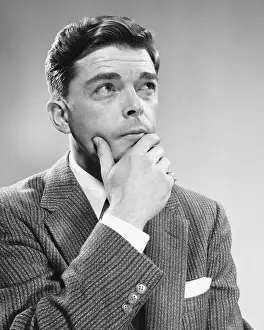 Man holding chin, looking upward
