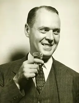 40 49 Years Prints: Man holding glass with spirit, (B&W), close-up