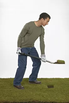 Man holding a spade with section of turf on the blade