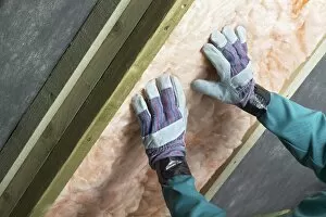 Man installing roof insulation in rafter, close-up