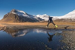 Images Dated 3rd November 2013: a man jumping across a water with snow mountain background